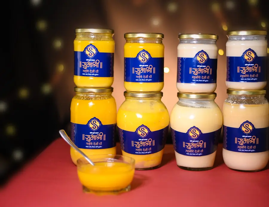 Eight jars of Subhashree cow and buffalo ghee stacked against warm lights