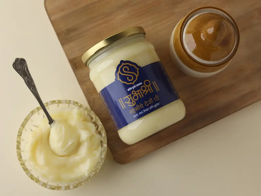 Buffalo ghee in a cut-glass bowl with a spoon, beside a jar of Subhashree ghee and a clay pot